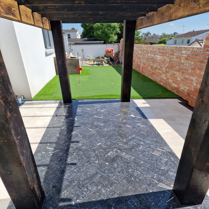 An outdoor patio area with Blue Limestone Setts arranged on the ground in herringbone style, showing a flamed finish and rich blue-grey colour.