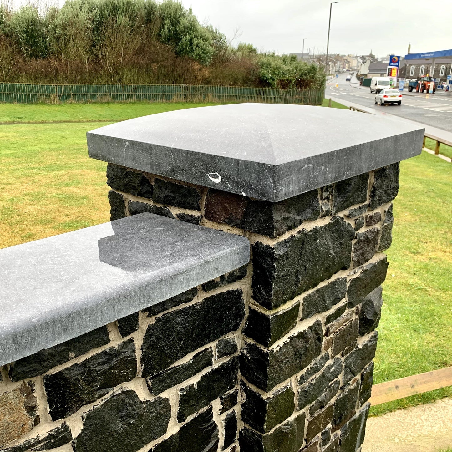 Dark stone wall with bespoke blue limestone pillar and wall capping. 