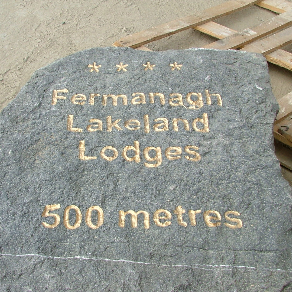 Decorative stone with engraved text 'Fermanagh Lakeland Lodges 500 metres' on a wooden pallet.