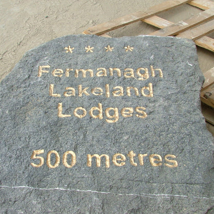 Decorative stone with engraved text 'Fermanagh Lakeland Lodges 500 metres' on a wooden pallet.