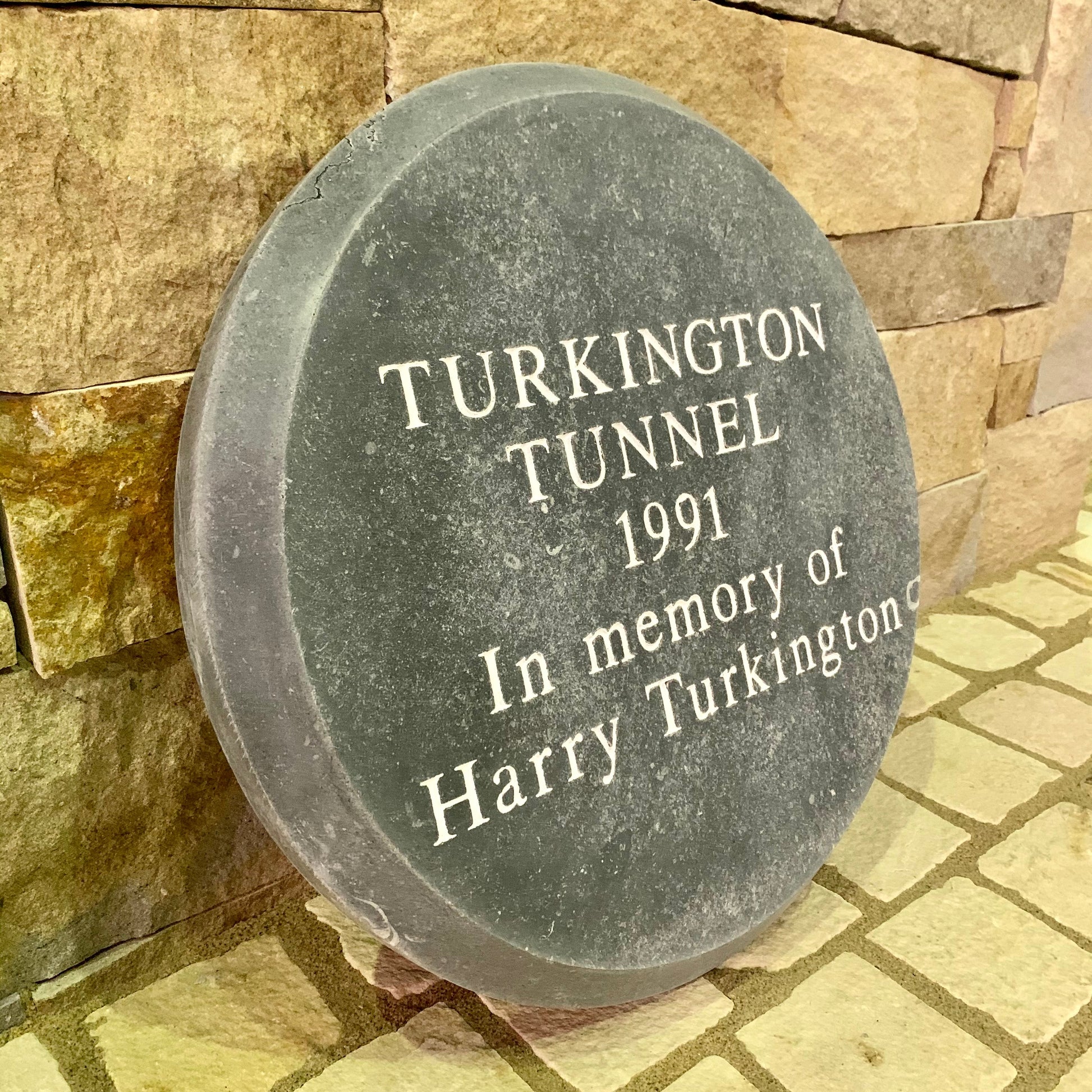 Bespoke Blue Limestone Memorial plaque for Turkington Tunnel dedicated to Harry Turkington, set against a stone wall.