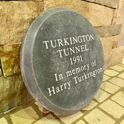 Bespoke Blue Limestone Memorial plaque for Turkington Tunnel dedicated to Harry Turkington, set against a stone wall.