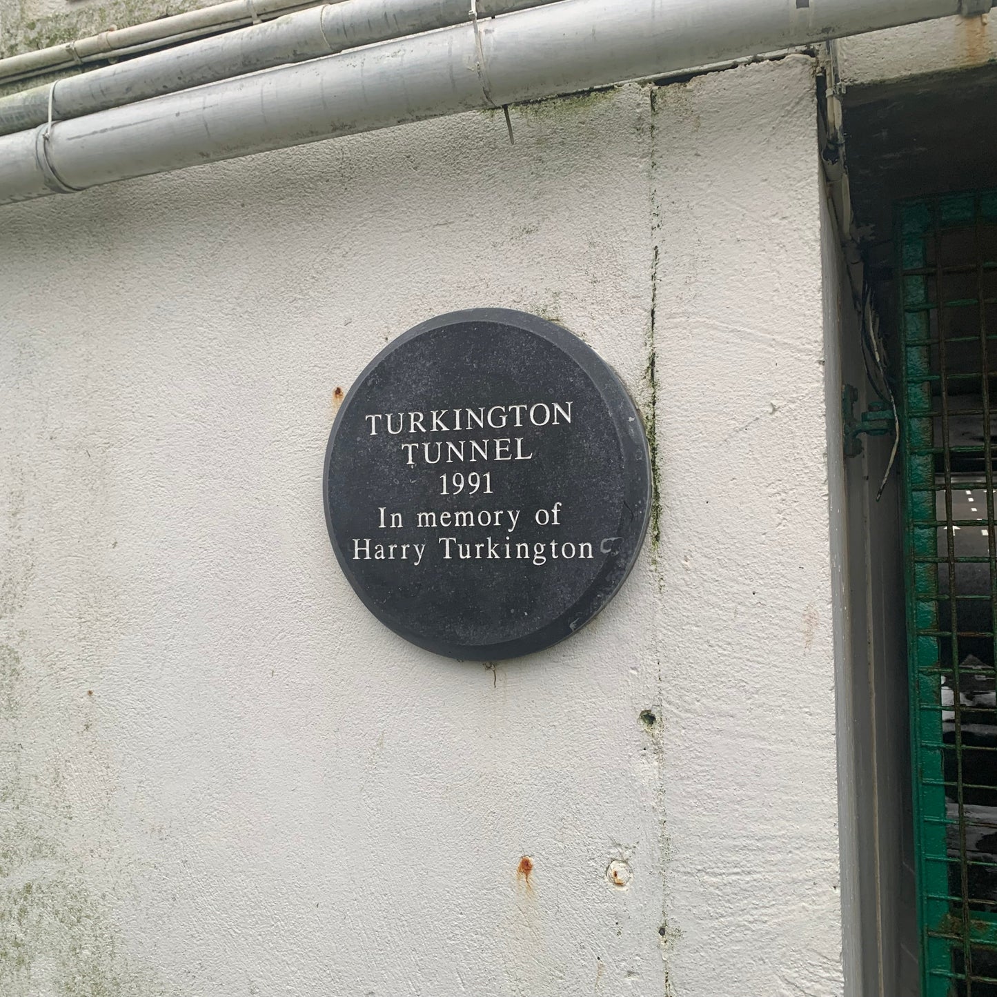 Plaque commemorating Turkington Tunnel with year 1991 and name Harry Turkington on a white wall.