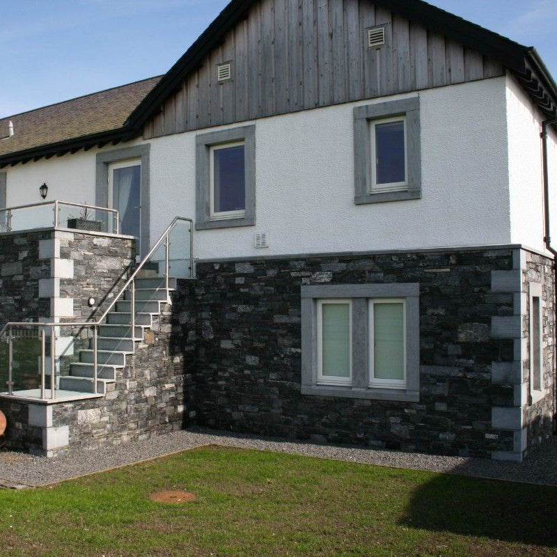 Modern house partly completed in stone with bespoke limestone quoins, surrounds, and steps. 