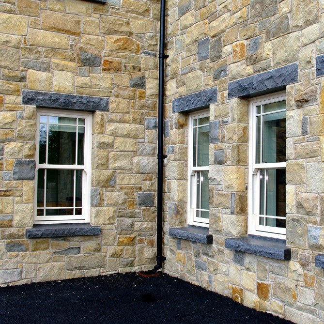 Stone building exterior with windows and bespoke limestone sills and lintels with a rockfaced finish