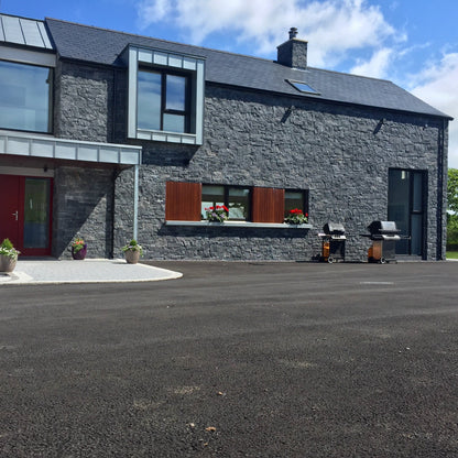Modern new build cladded in Blue Limestone Stoneer Cladding with tarmac street. 