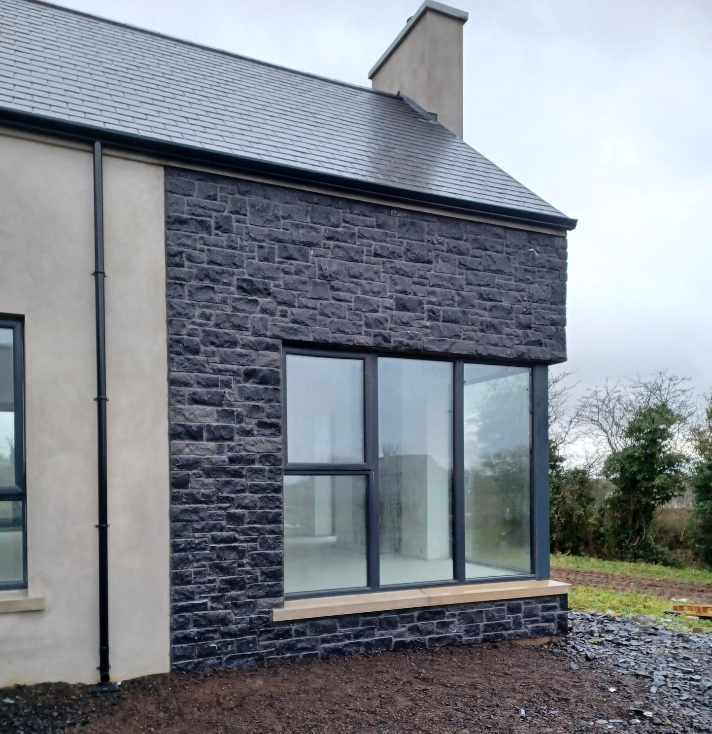 New build under construction with blue limestone feature wall completed using stoneer cladding. 