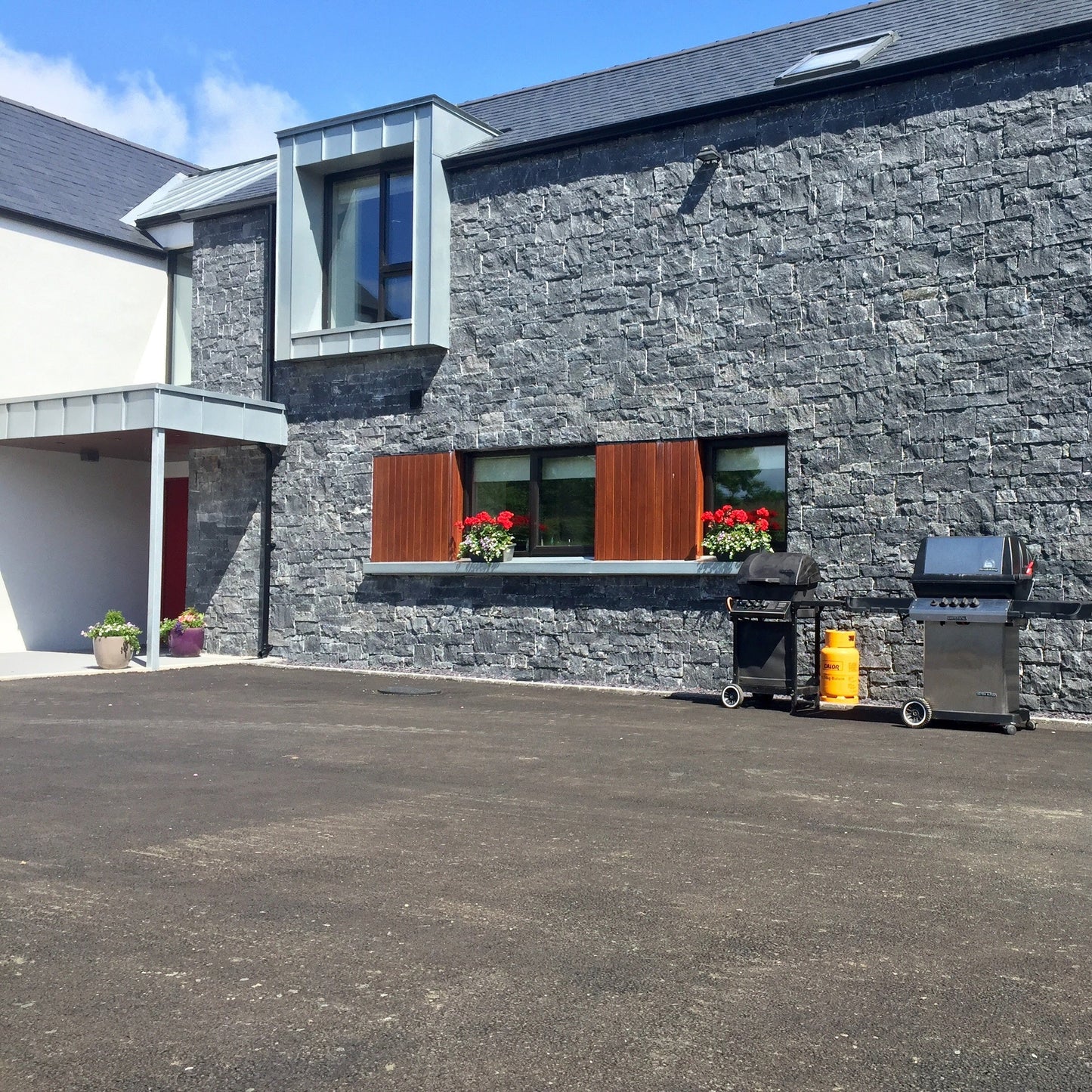 Modern new build cladded in Blue Limestone Stoneer Cladding with tarmac street.