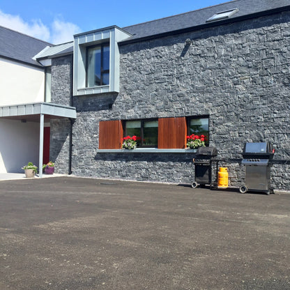 Modern new build cladded in Blue Limestone Stoneer Cladding with tarmac street.