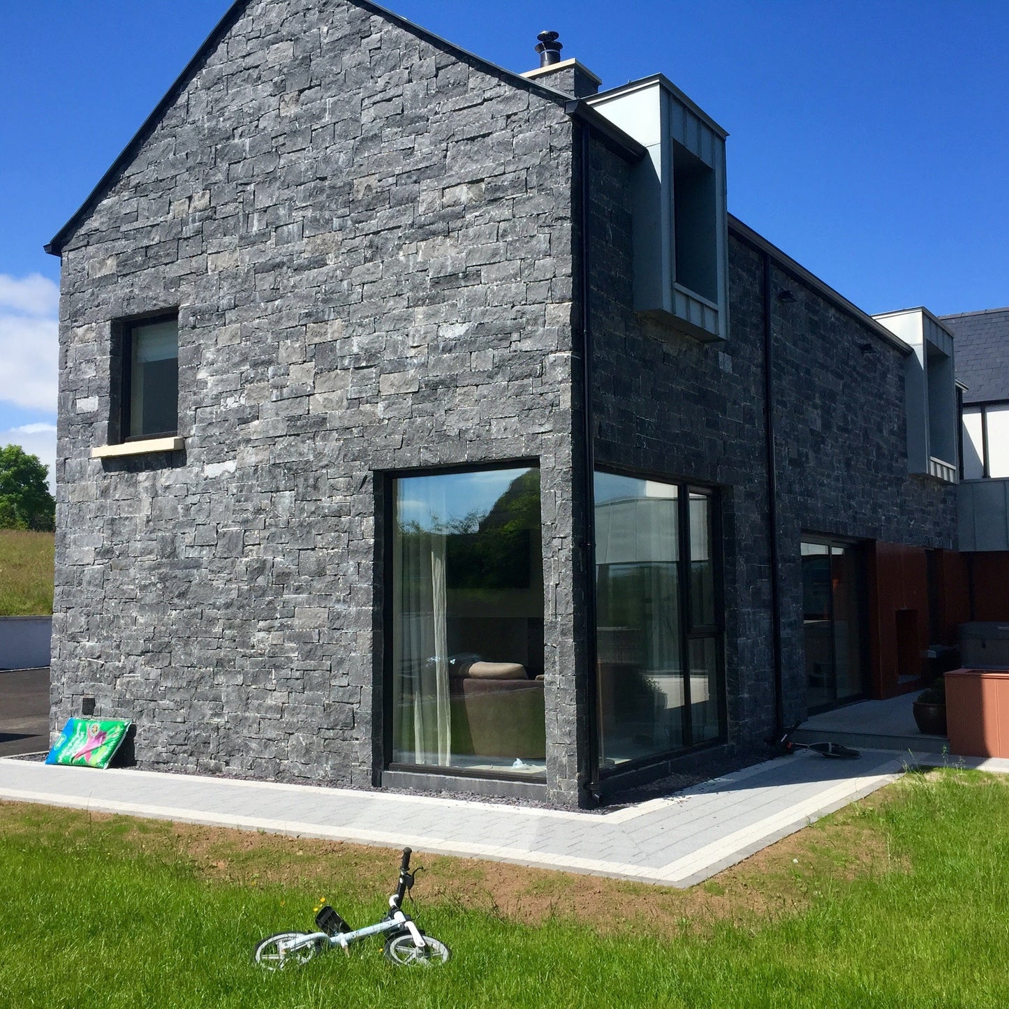 Modern new build cladded in Blue Limestone Stoneer Cladding with tarmac street.