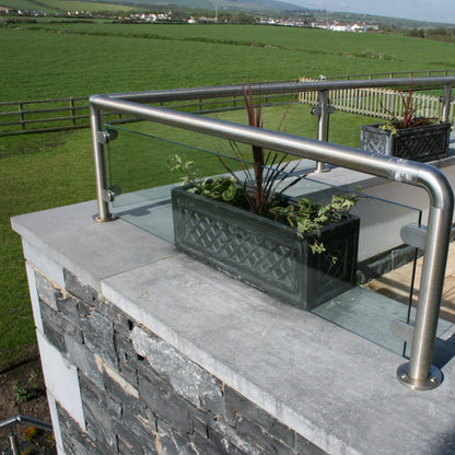 Terrace with glass panels and metal railings on top of bespoke blue limestone wall capping overlooking a green landscape