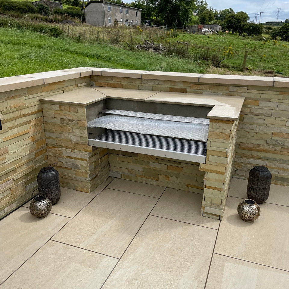BBQ and stone wall in a paved patio area. Paving is Camel Jewel Range Porcelain Paving. 