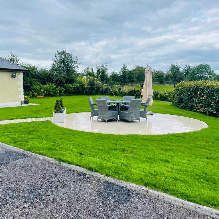 Backyard with patio set, umbrella, and garden furniture near a house. Paving is Camel Jewel Range Porcelain Paving. 