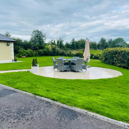 Backyard with patio set, umbrella, and garden furniture near a house. Paving is Camel Jewel Range Porcelain Paving. 