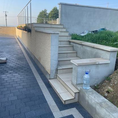 Steps leading up to large patio area surround by glass balustrade. Steps completed using Camel Jewel Range Porcelain Paving Tiles. 