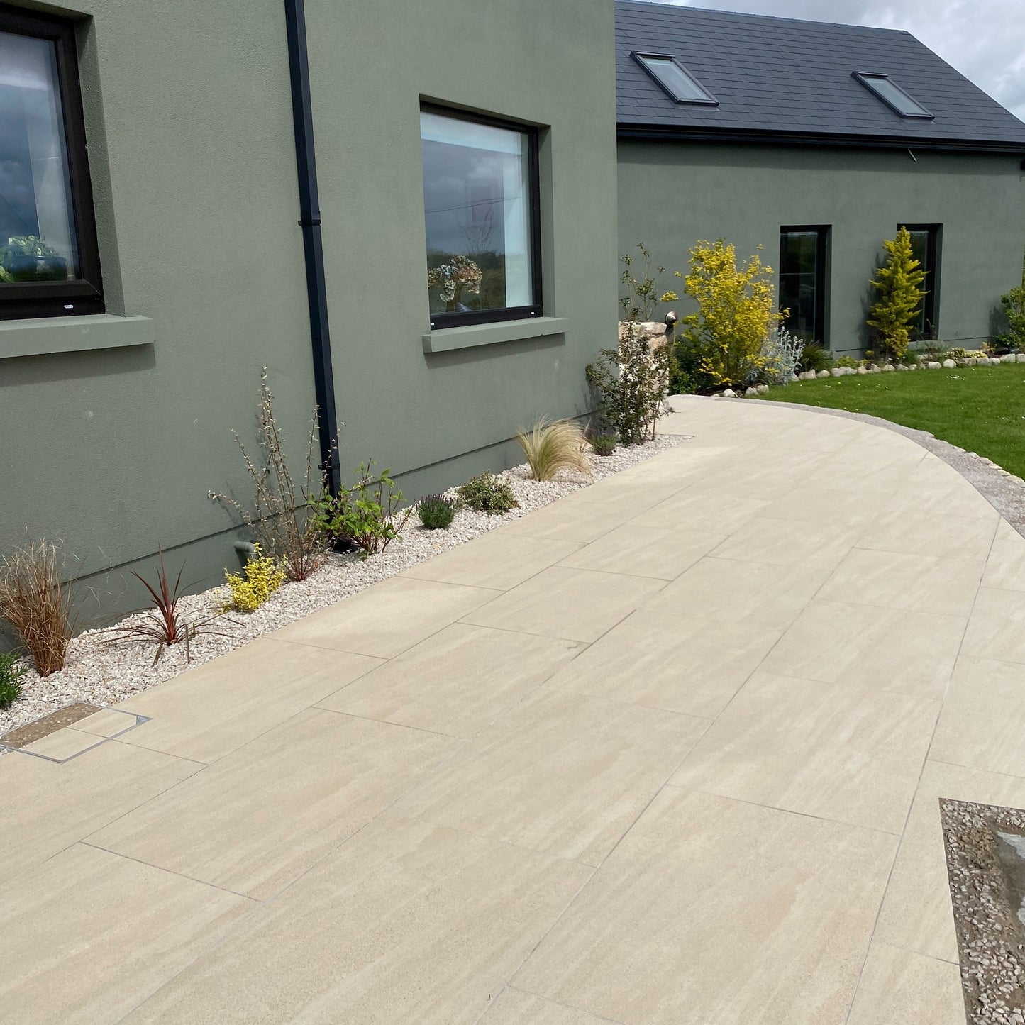 An outdoor patio installation of Camel porcelain paving tiles in a garden setting, with a neutral beige colour.