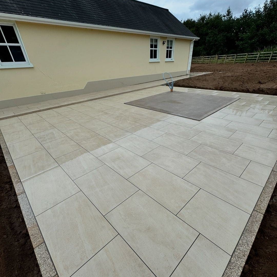 Large patio featuring Camel Jewel Range Porcelain Paving and Gold Granite Edging. Garden landscaping under construction in the background