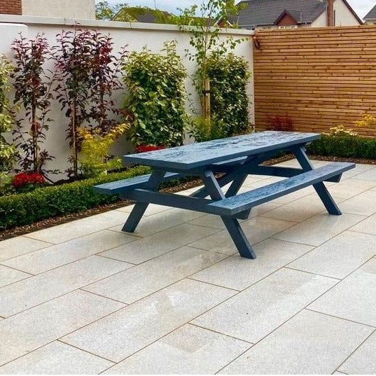 Patio with picnic bench and planting and wooden fence in the background. Paving is Camel Jewel Range Porcelain Paving Tiles. 