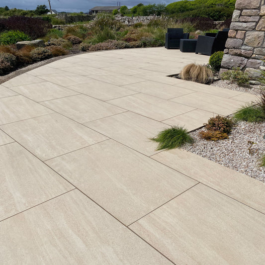 An outdoor installation of Camel porcelain paving tiles in a garden setting, with a neutral beige colour.