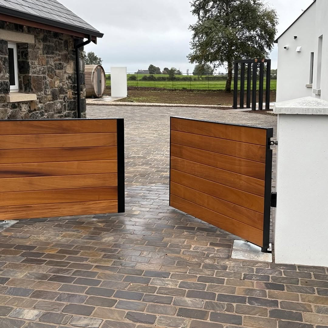 Stone building and wooden gate with cobbled driveway featuring Cider Black Sandstone Paving Setts in 200 x 100mm. 