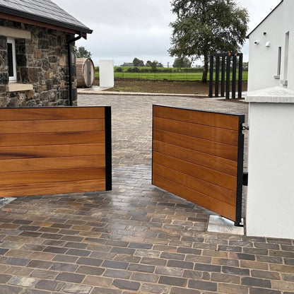 Stone building and wooden gate with cobbled driveway featuring Cider Black Sandstone Paving Setts in 200 x 100mm. 