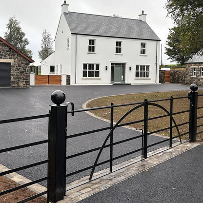 White house with a grey roof and black gate in a residential area. Cobble detail at gate entrance featuring Cider Black Sandstone Paving Setts. 