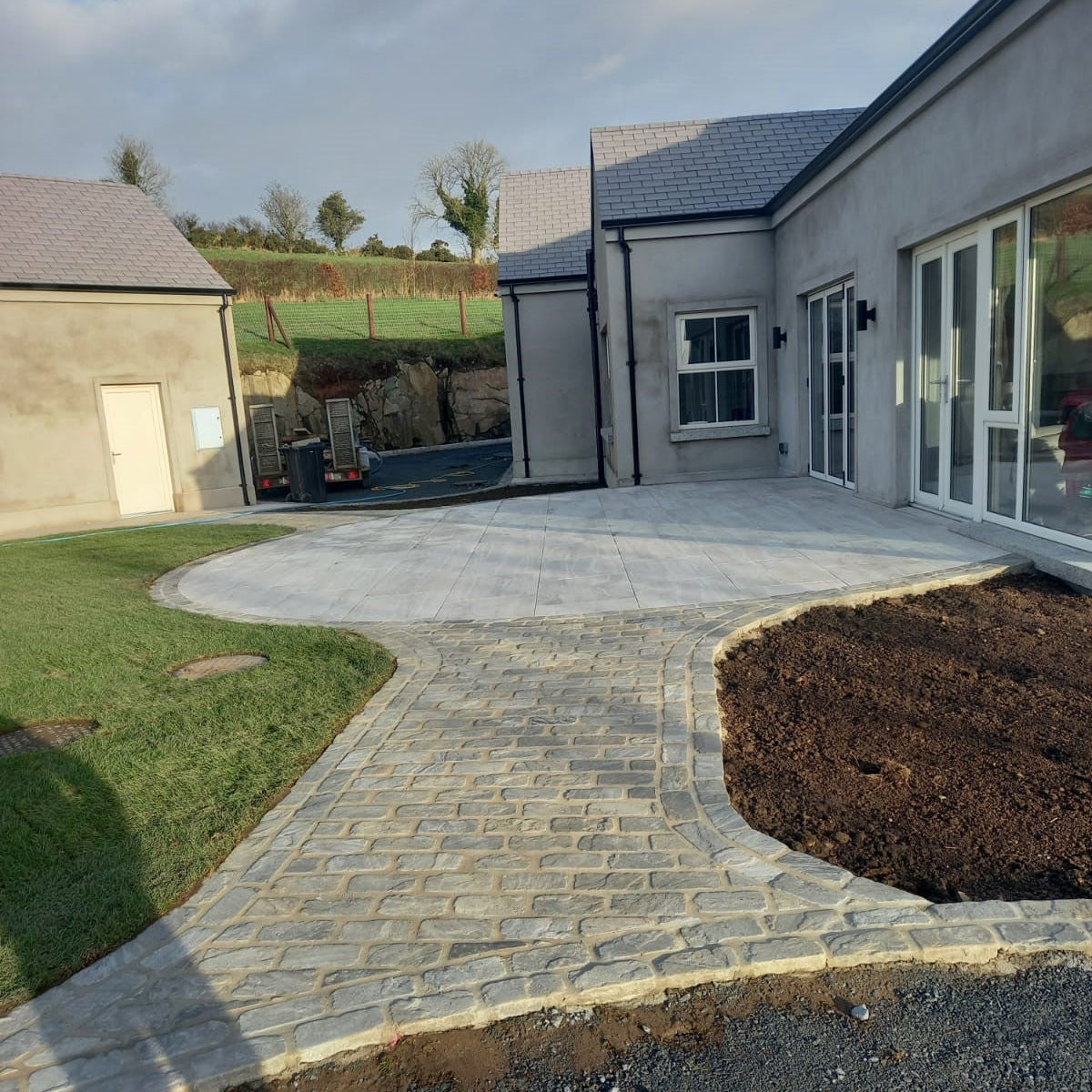 Cobbled pathway leading to patio of new build completed using Cider Black Sandstone Paving Setts. 