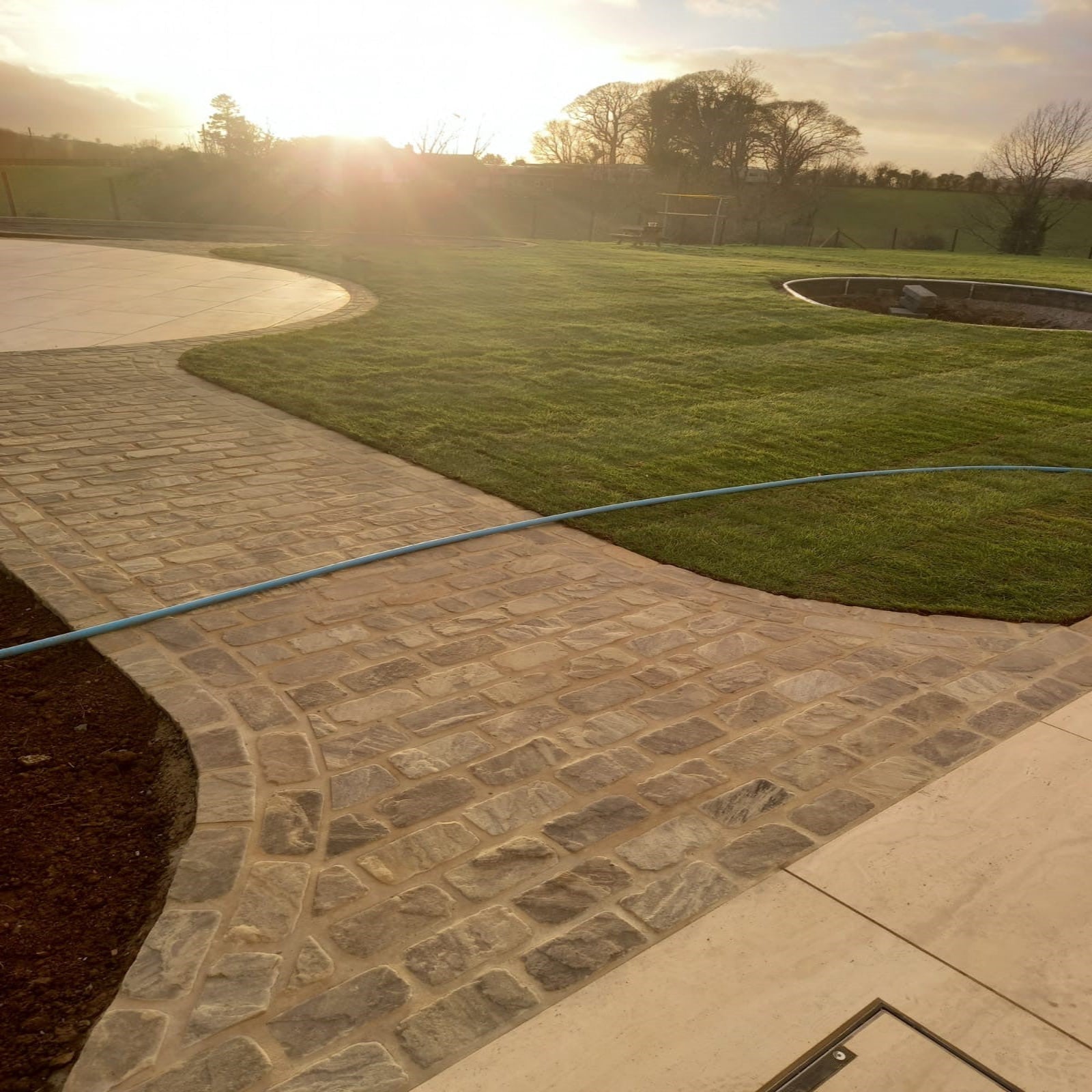 Pathway leading to circular patio area featuring Cider Black Sandstone Setts. 