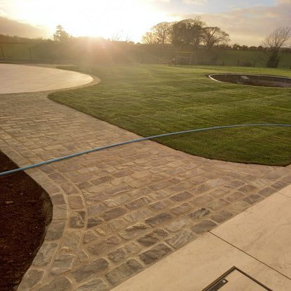 Pathway leading to circular patio area featuring Cider Black Sandstone Setts. 