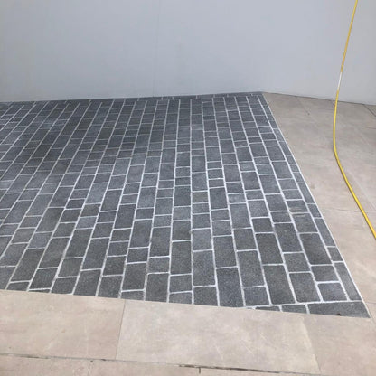 A pathway photographed dry laid out with Coachman's Black Granite Paving Setts, showing a contemporary look with a flamed surface finish and tumbled edges.