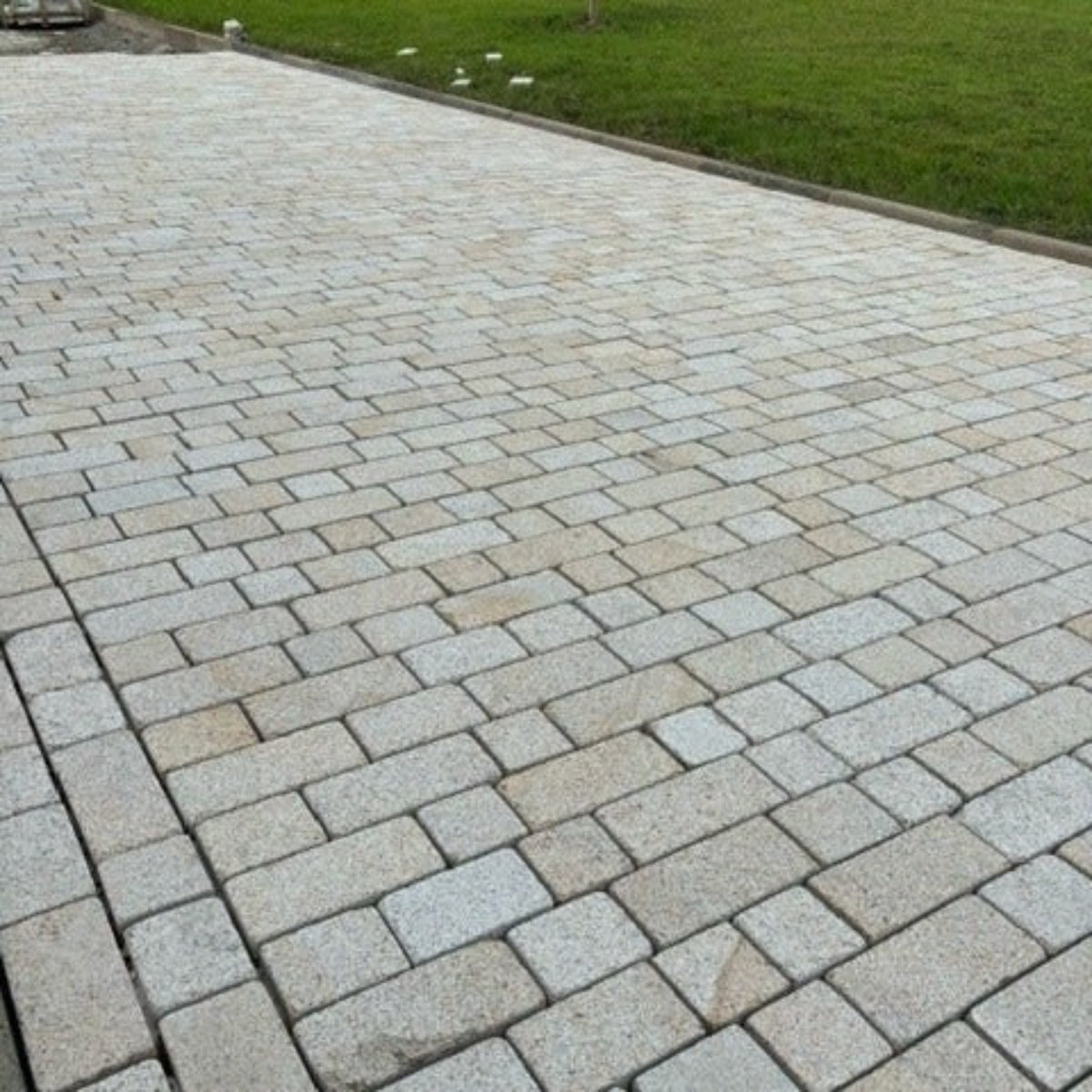 A pathway laid out with Coachman's Gold Granite Paving Setts, showing a contemporary look with a bush hammered surface finish and tumbled edges.