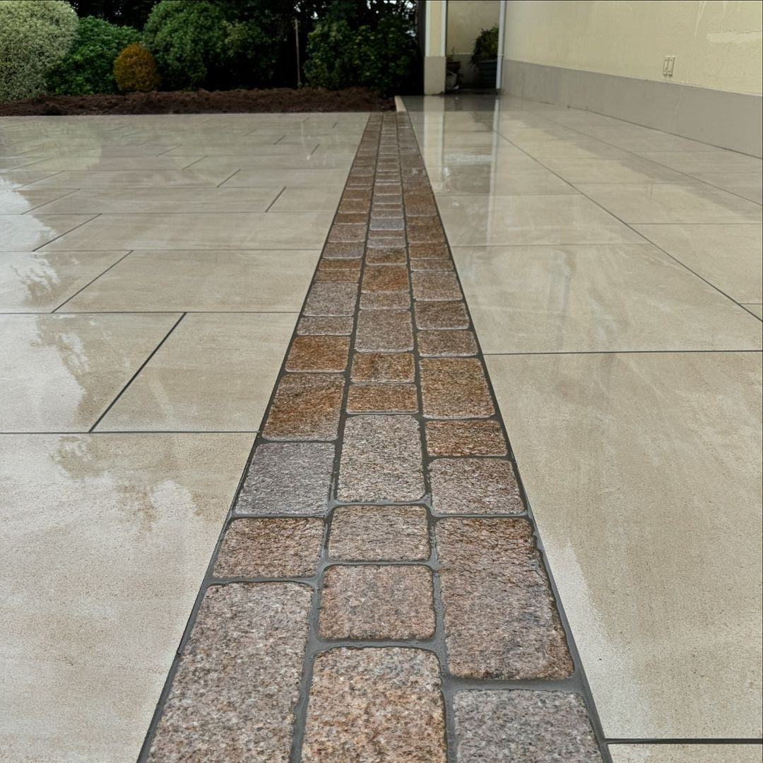Porcelain patio with edging in Coachman's Gold Granite Paving Setts, showing a contemporary look with a bush hammered surface finish and tumbled edges.