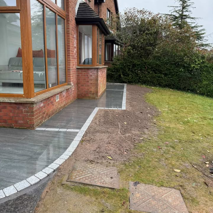 House exterior with a patio area and garden. Coachman's Silver Granite paving setts were used to border the patio and grass. 