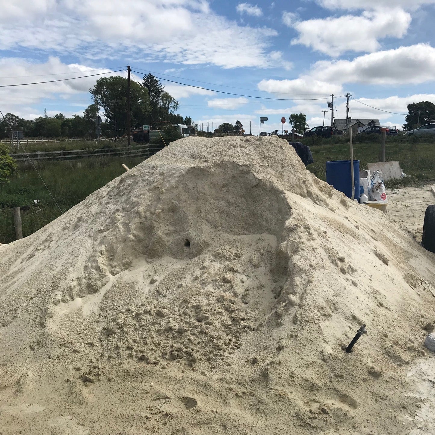 Large pile of sand with a blue sky and clouds in the background