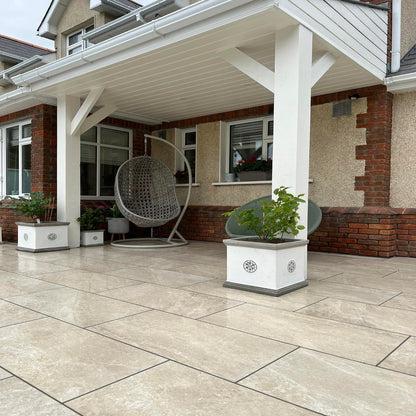 Patio area under a roof canopy of a red brick house completed using Cream Twice Qz Range Porcelain Paving Tiles. 