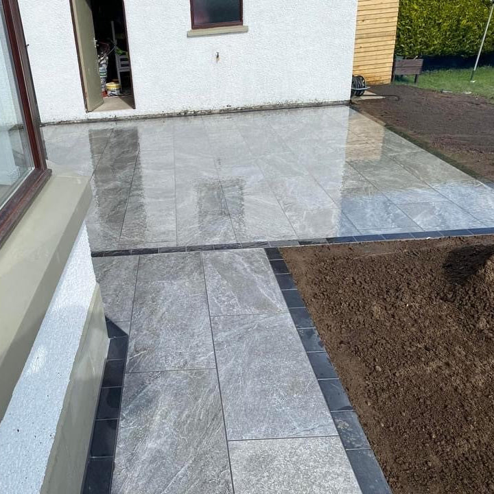Patio area and pathway bordered with black cobbles. Paving is Dark Twice Qz Range Porcelain Paving Tiles.  