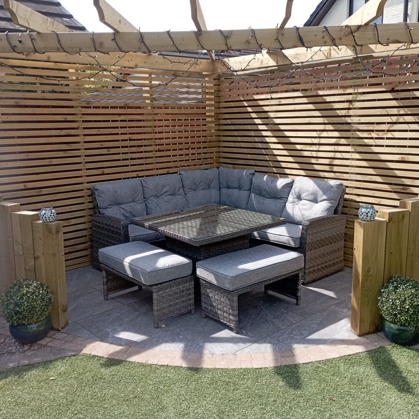 Small patio area with wooden pergola and wicker garden furniture. Paving underneath is Dark Twice Qz Range Porcelain Paving Tiles. 