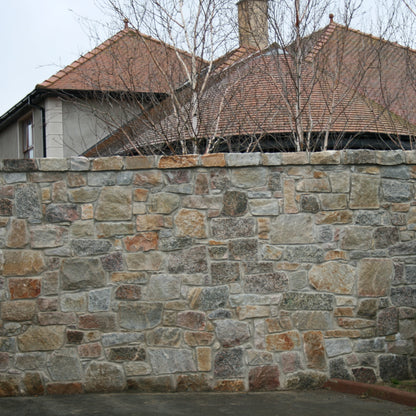 Stone wall with a house and trees in the background
