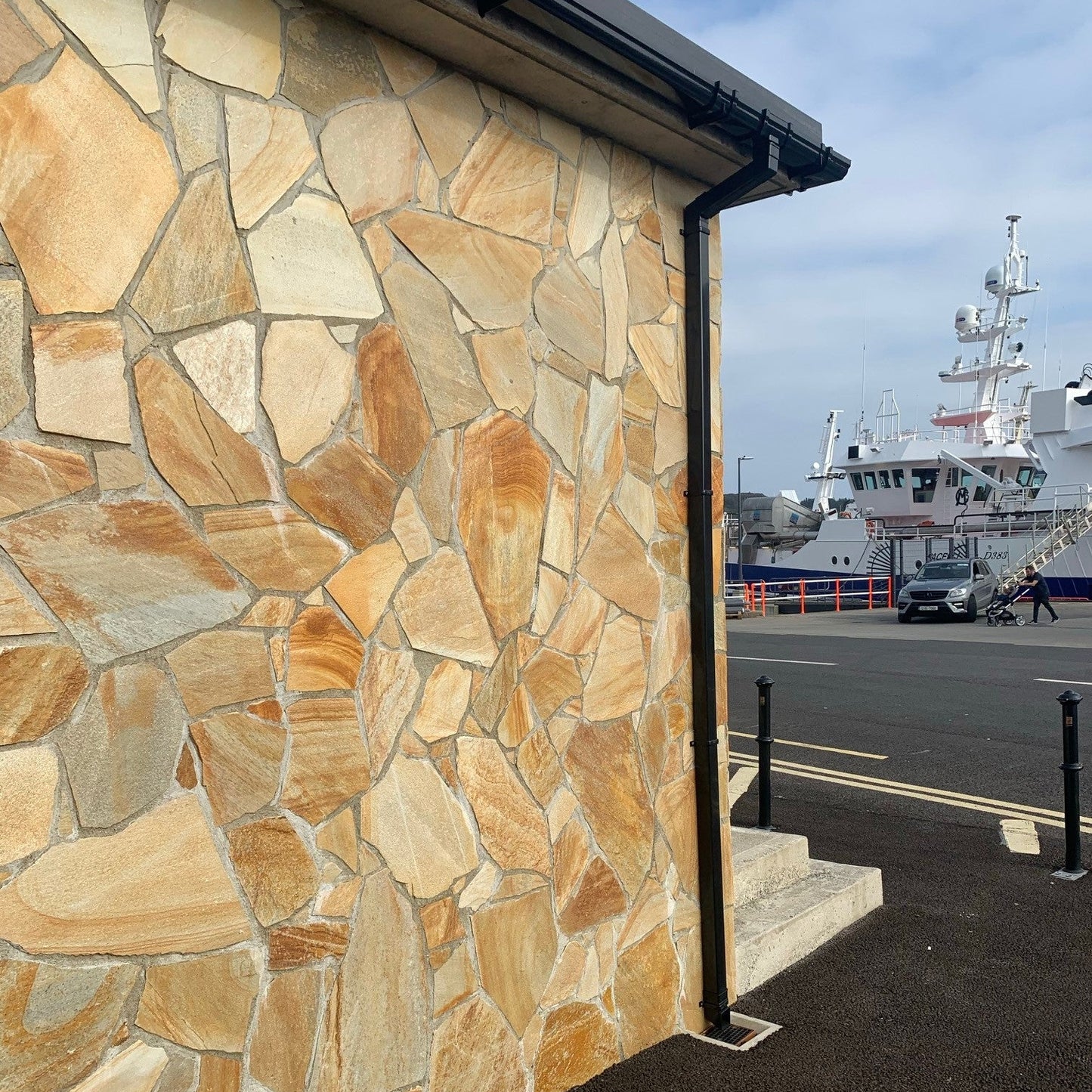 Stone wall completed using Donegal Quartzite Cladding . There is a view of a harbour and a ship in the background 