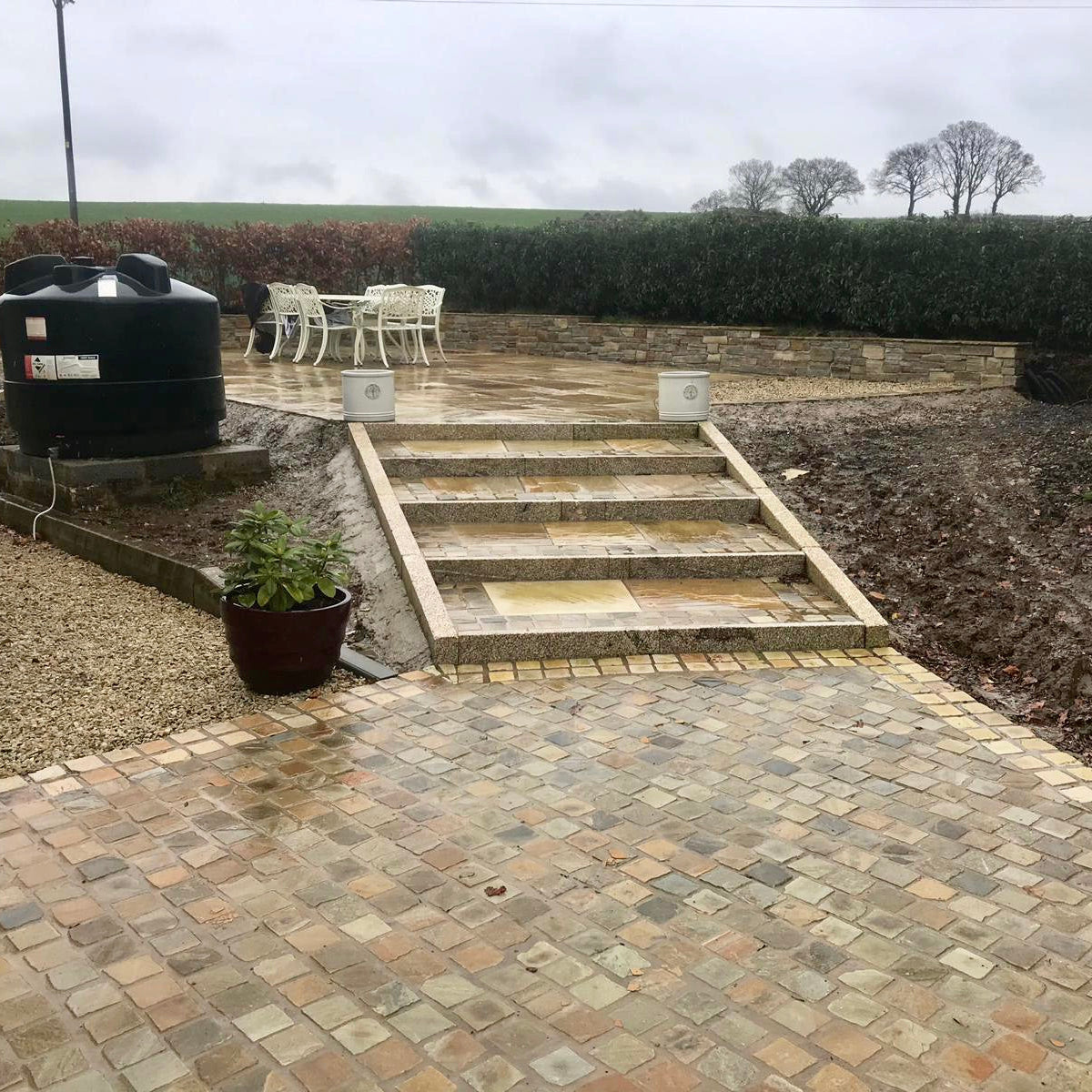 Patio with steps featuring Donegal Quartzite Cobbles in 100 x 100mm size and Tinted Mint Sandstone setts on the edge of patio. 