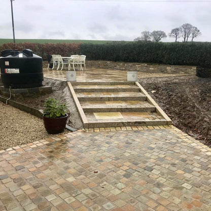 Patio with steps featuring Donegal Quartzite Cobbles in 100 x 100mm size and Tinted Mint Sandstone setts on the edge of patio. 