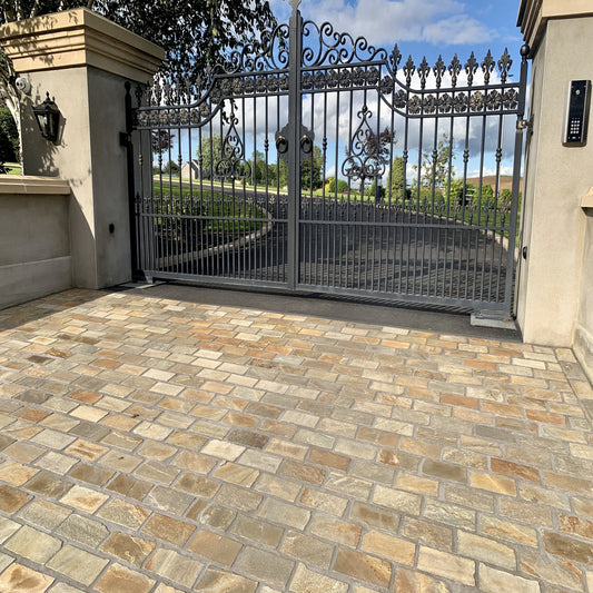 A cobblestone pathway made using Donegal Quartzite Cobbles in 200 x 100mm, leading up to a decorative metal gate.