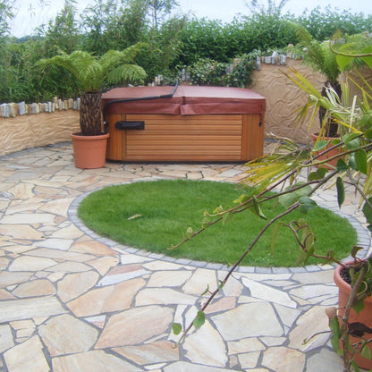 Patio area with hot tub and circular patch of grass in the centre. Paving is Donegal Quartzite Crazy Paving.  