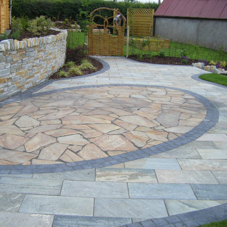 Patio area with circular design finished with Donegal Quartzite Crazy  Paving enclosed with black granite cobbles. 