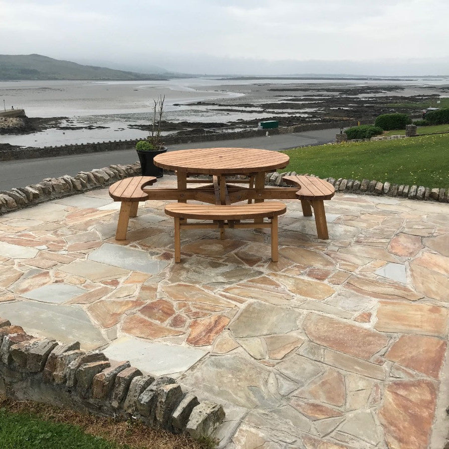 Irregular golden brown Donegal Quartzite Crazy paving at the Waterfront hotel with a wooden table and benches on top of it, overlooking the sea in Dungloe, Co. Donegal. 