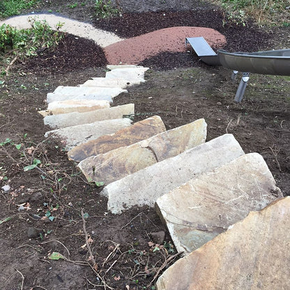 Stone steps leading up a hill with mulch and garden area in the background