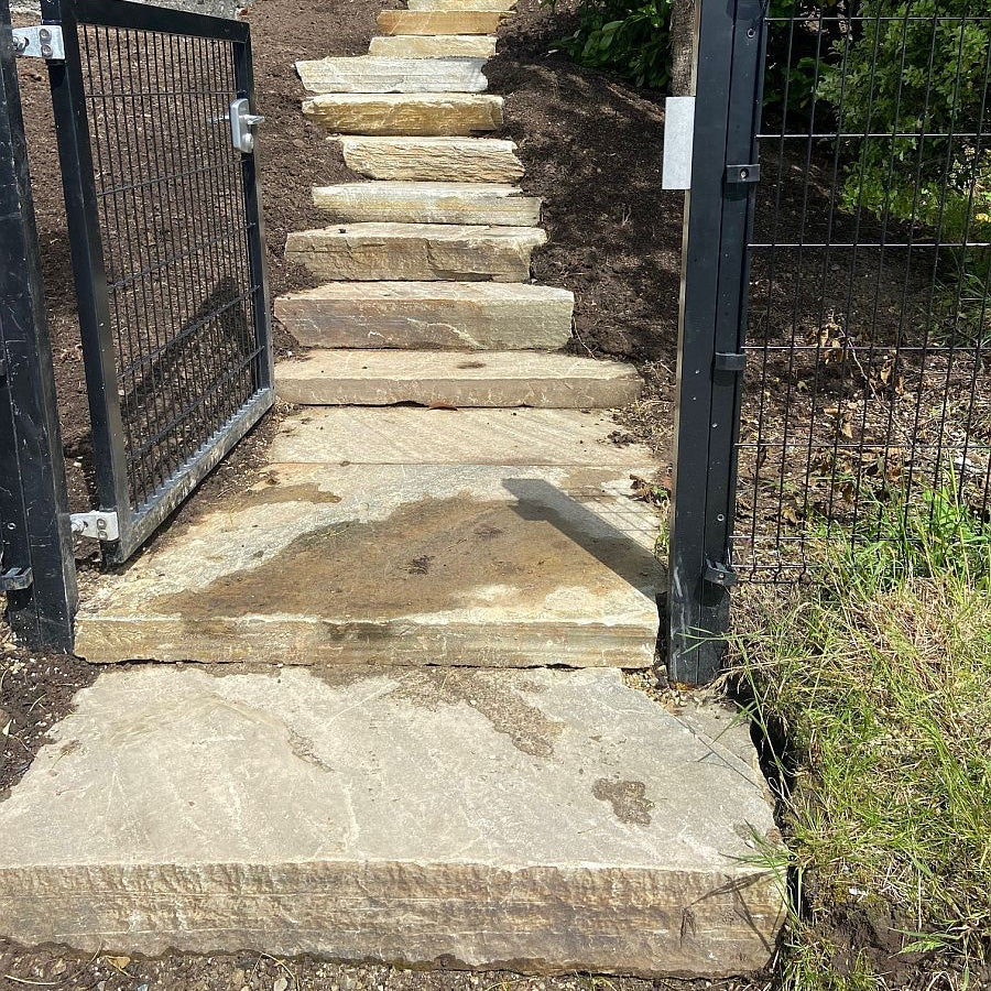 Stone steps with a metal gate on a sunny day.