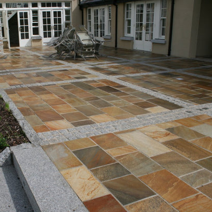 Large patio area with garden furniture finished in Donegal Quartzite Sawn Paving and Silver Granite Cobbles 100x100mm. 