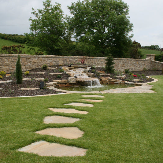 Garden with Donegal Quartzite Stepping stones leading to a small waterfall feature and stone wall.