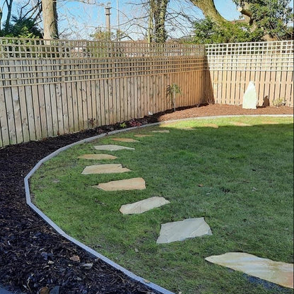 Circular garden with Donegal Quartzite Stepping Stones and a tall fence in the background. 